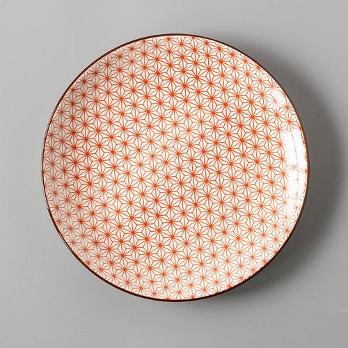 Round plate with orange geometric pattern on a gray background