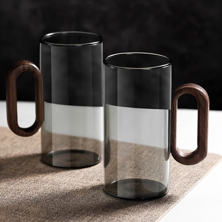 Two glass mugs with wooden handles on a textured surface.