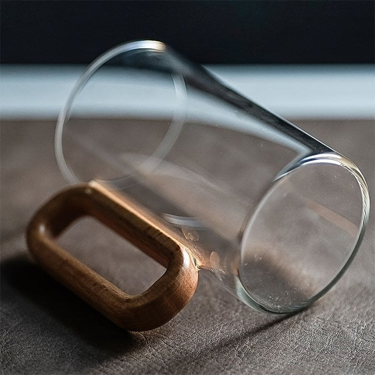 Clear glass tumbler with wooden handle on a dark surface