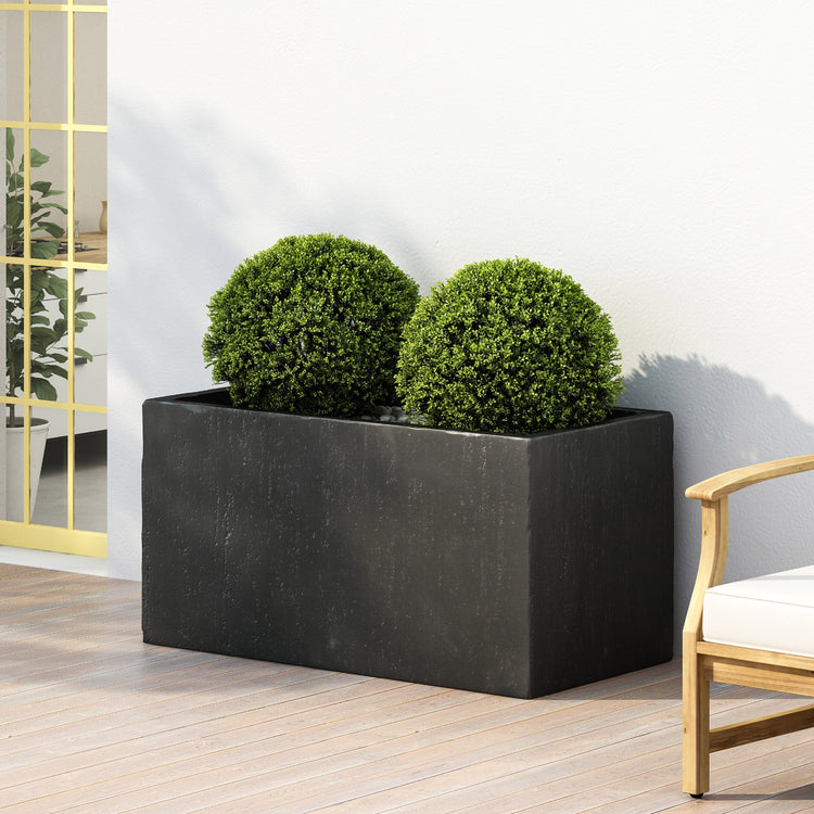 Black rectangular planter with two green spherical plants on a wooden deck.