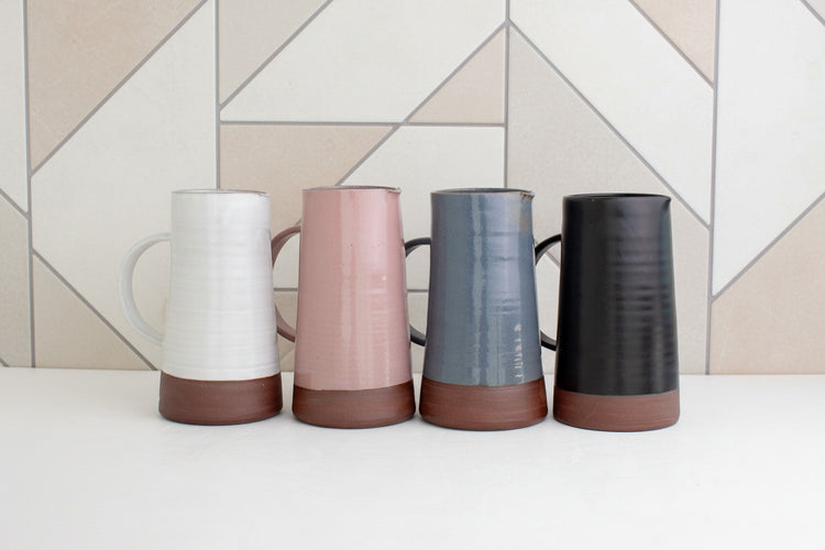 Group of multi-colored ceramic pitchers by Black Oak Art, showcasing modern handcrafted designs in vibrant hues.