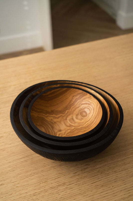 Set of two half charred ashwood nesting bowls by CREATING COMFORT, showcasing smooth, natural wood with a dark charred finish.