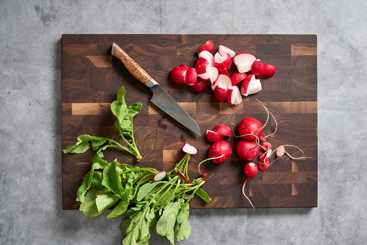 Steelport Knife Co. 4-inch paring knife slicing fresh radishes on a cutting board, showcasing a sharp kitchen knife for precise prep.