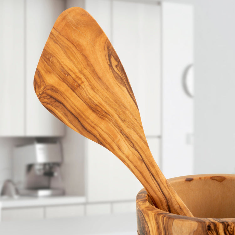 Wooden spatula in a wooden holder with a kitchen background
