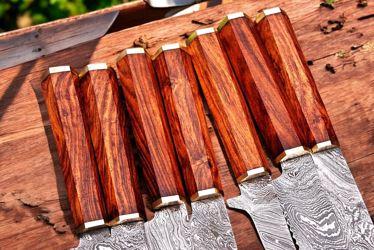 Premium Damascus kitchen knives set with handmade, sharp blades and wooden handles, displayed on a wooden cutting board.