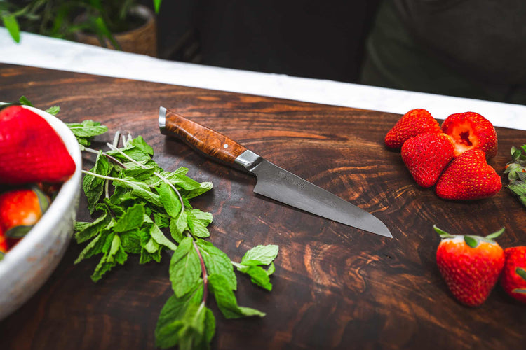 Steelport Knife Co. 4-inch paring knife slicing a strawberry, showcasing sharp blade and compact kitchen knife design.