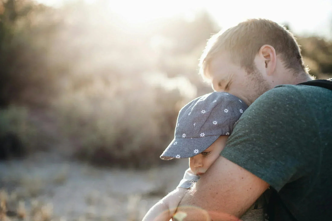 Father hugging young child outdoors during sunset, capturing a heartfelt Father’s Day moment filled with warmth and connection.
