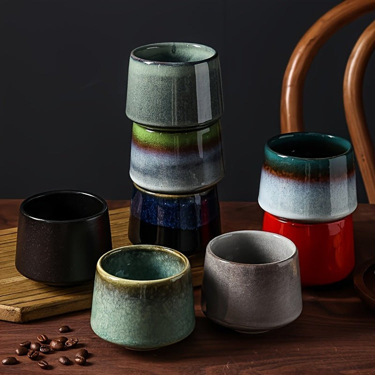 Set of ceramic cups with multicolored glaze on a wooden surface with coffee beans.