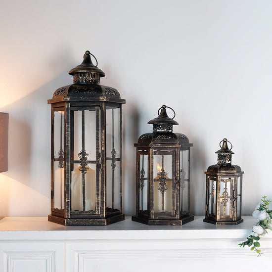 Set of 3 outdoor decorative candle lanterns with large metal frames and glass panels for patio or garden decor.