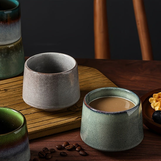 Ceramic cups with different finishes on a wooden surface with coffee beans.