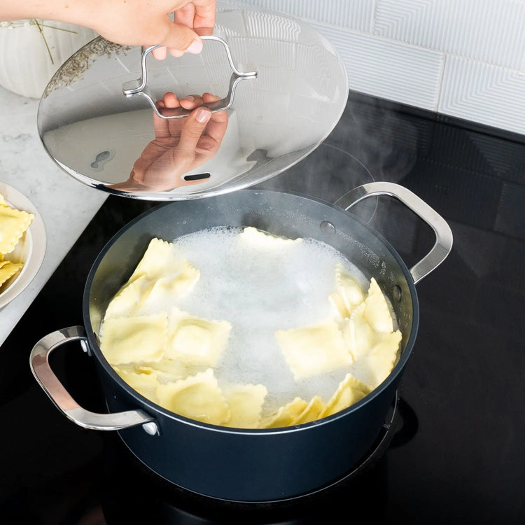 Alva Cookware 4-piece set with matching pots and pans, stainless steel handles, and glass lids on a kitchen countertop.