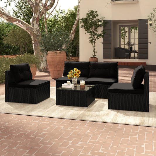 Black outdoor furniture set with a coffee table and flowers on a patio.