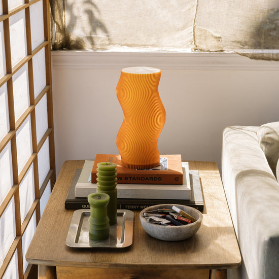 Terra Labs Woogie table lamp with a playful, colorful base and a white fabric lampshade on a wooden table.