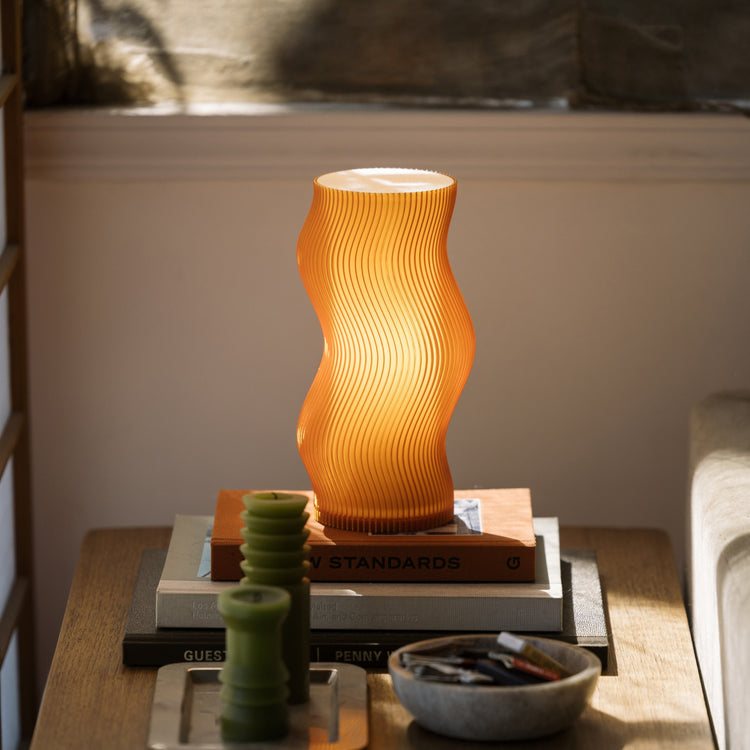 Terra Labs Woogie Table Lamp with soft glowing light and modern design, placed on a wooden side table.