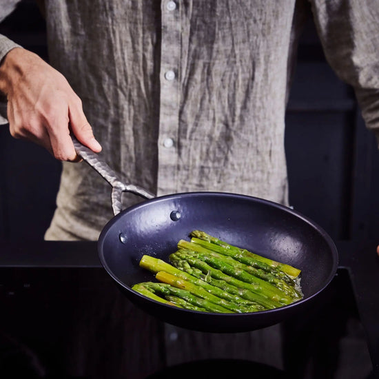 Alva Cookware frying pan with non-stick surface and stainless steel handle, shown on a kitchen countertop.