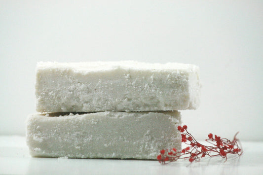 Two stacked soap bars with a small red plant on a white background