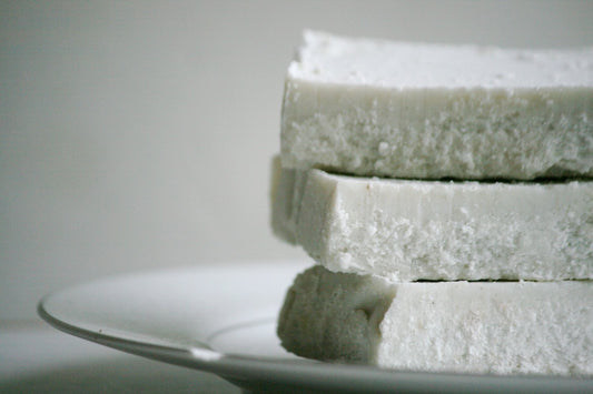 Stack of white soap bars on a gray plate with a neutral background