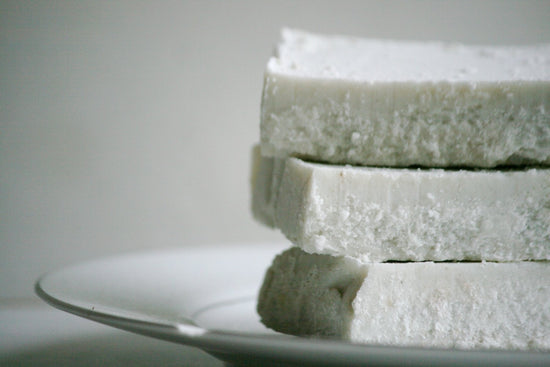 Stack of white soap bars on a gray plate with a neutral background