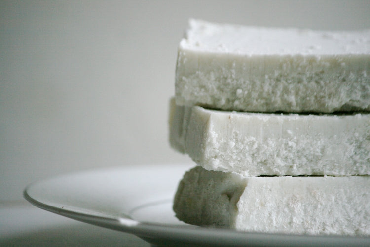 Stack of white soap bars on a gray plate with a neutral background