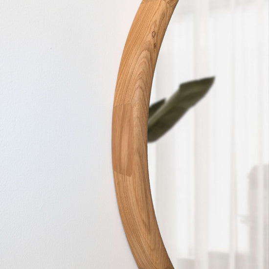 VARBROS THE KOLO wall mirror with a sleek, modern design reflecting natural light in a contemporary room setting.