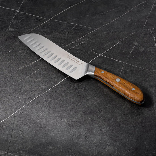 Swiss Diamond 7-inch Damascus Santoku Knife with sharp blade, ergonomic handle, ideal for slicing and chopping in the kitchen.