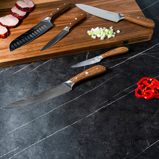 Swiss Diamond Damascus 5-piece knife set displayed with stainless steel blades and wooden handles on a cutting board.