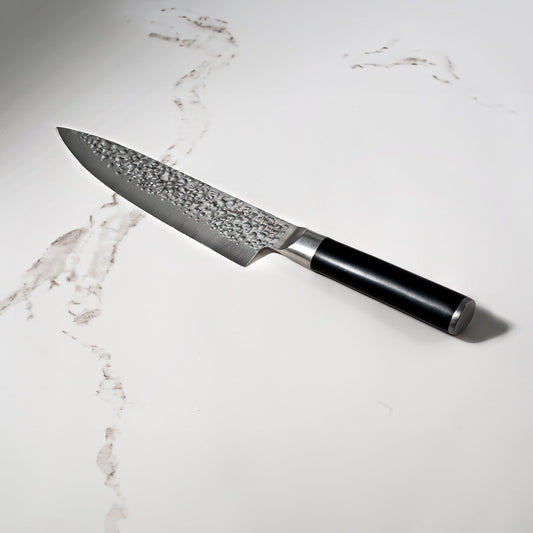 Swiss Diamond 8-inch hammered chef knife with white marble handle and blade, ideal for precise kitchen slicing and chopping.