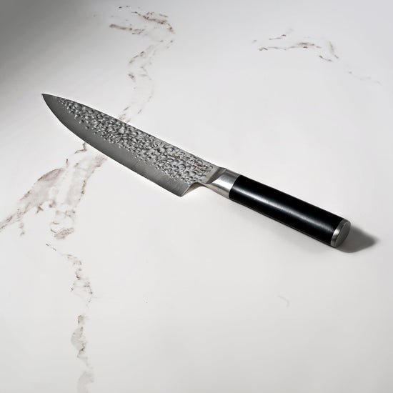 Swiss Diamond 8-inch hammered chef knife with white marble handle and blade, ideal for precise slicing and culinary tasks.