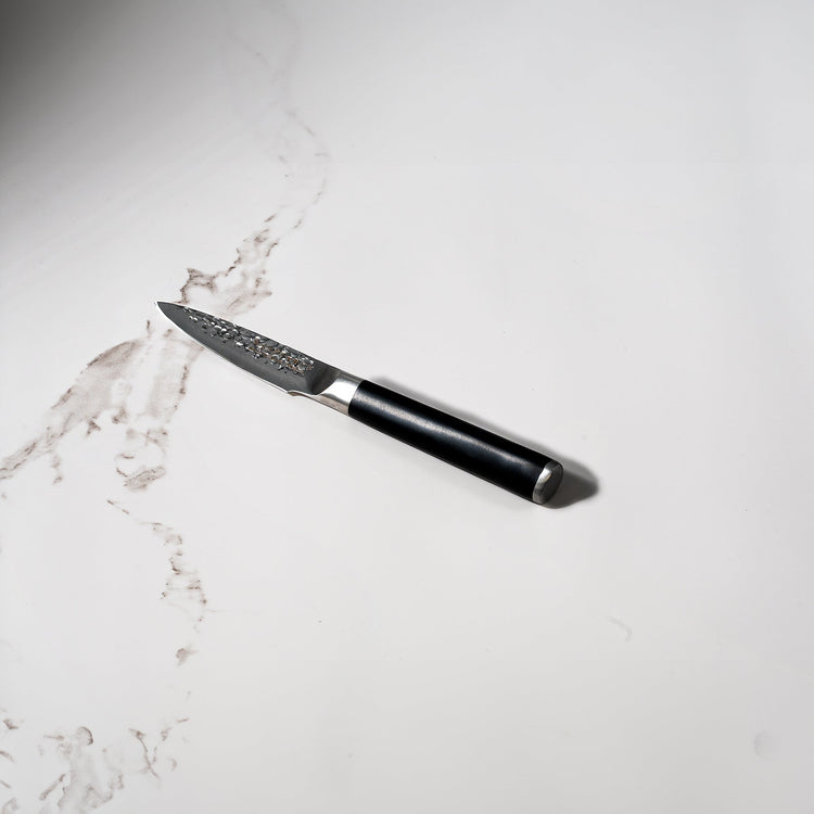 Swiss Diamond 4-inch hammered paring knife with white marble handle, showcasing a sleek, precision-forged kitchen knife design.
