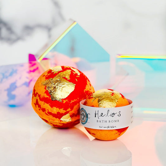 Bath bomb with gold accents and a visible label on a reflective surface.