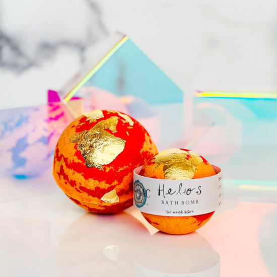 Bath bomb with gold accents and a visible label on a reflective surface.