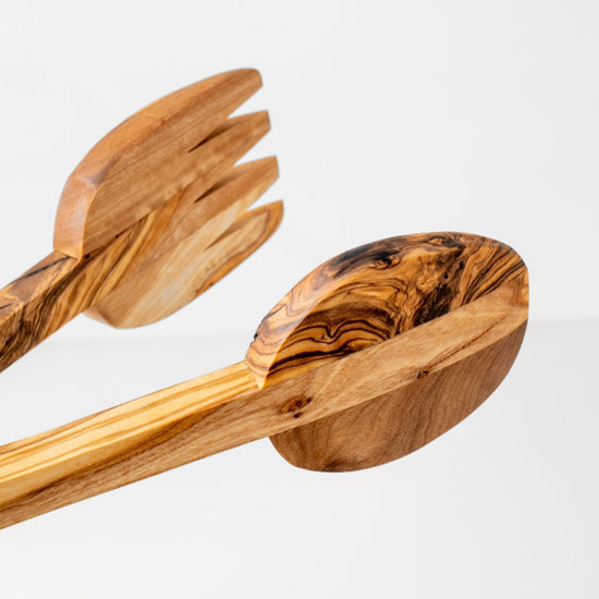 Wooden salad servers with a wavy pattern on a light gray background