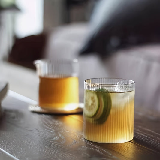 Two glasses of iced drinks with lime slices on a wooden surface.