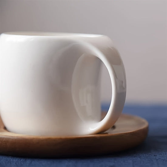 White ceramic cup on a wooden saucer with a blurred background