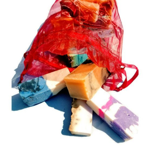 Assorted colorful soap bars in a red drawstring bag on a white background