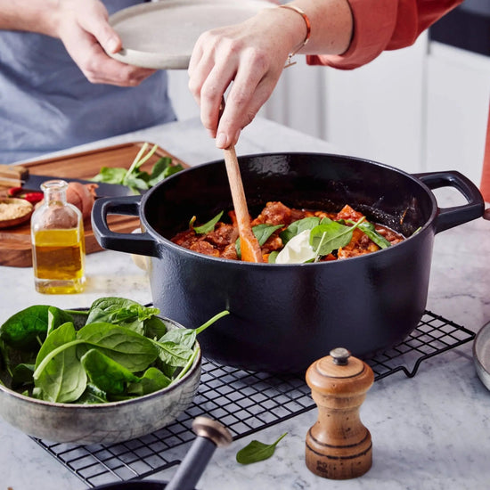 Alva Cookware 5 QT round Dutch oven with black enamel exterior and sturdy handle, ideal for baking and slow cooking.
