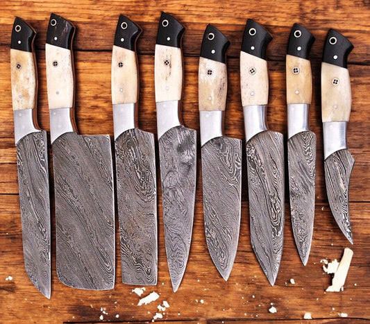 Set of handmade Damascus kitchen knives with sharp blades and wooden handles, displayed on a cutting board.