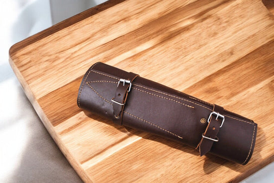 Handmade Damascus steel kitchen knives set with exotic wood handles displayed on a wooden surface.