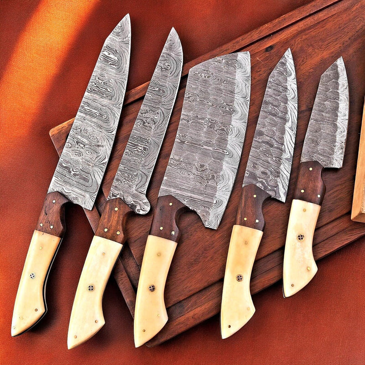 Handmade Damascus kitchen knives set with bone and rosewood handles, featuring intricate blade patterns and polished wooden scales.