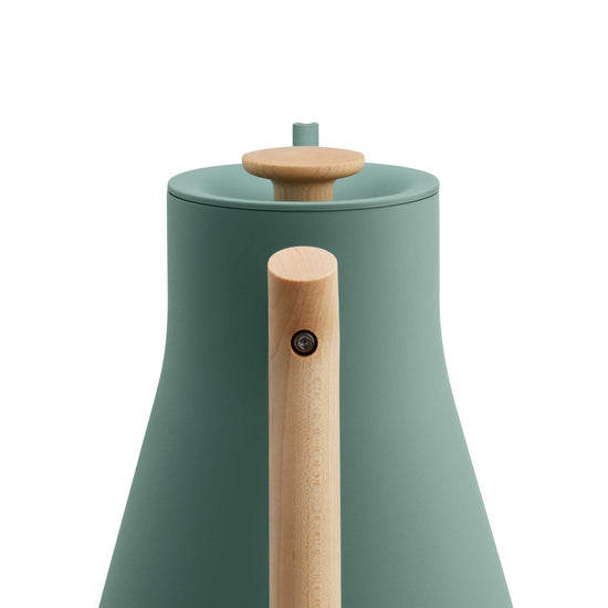 Fellow Stagg EKG Pro electric kettle in smoke green with maple handle, featuring a sleek design and digital temperature control.