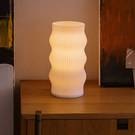 Terra Labs Wub Table Lamp with a modern design, featuring a sleek base and a rounded, colorful lampshade on a wooden surface