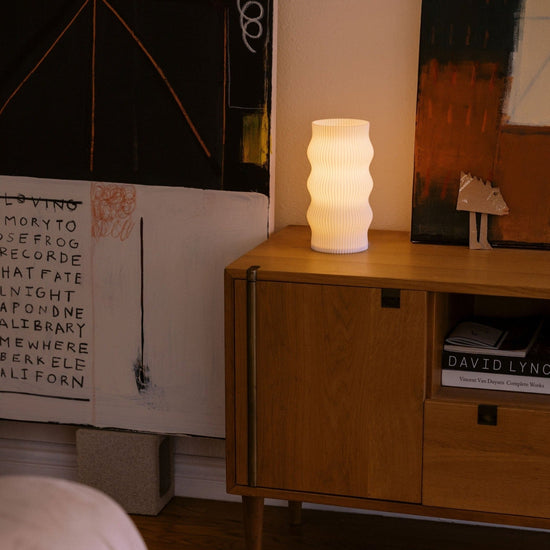 Terra Labs Wub Table Lamp with sleek modern design and soft ambient lighting on a wooden bedside table.